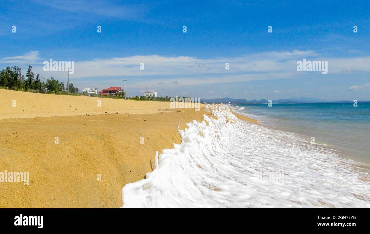 onde schiumose che si infrangono sulla spiaggia di sabbia in una giornata di sole Foto Stock