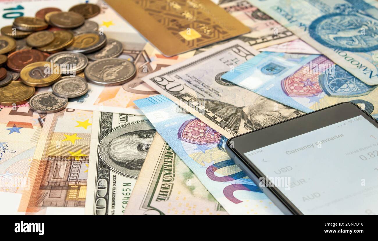 immagine ravvicinata di carte di credito, smartphone, monete e banconote di diverse valute Foto Stock