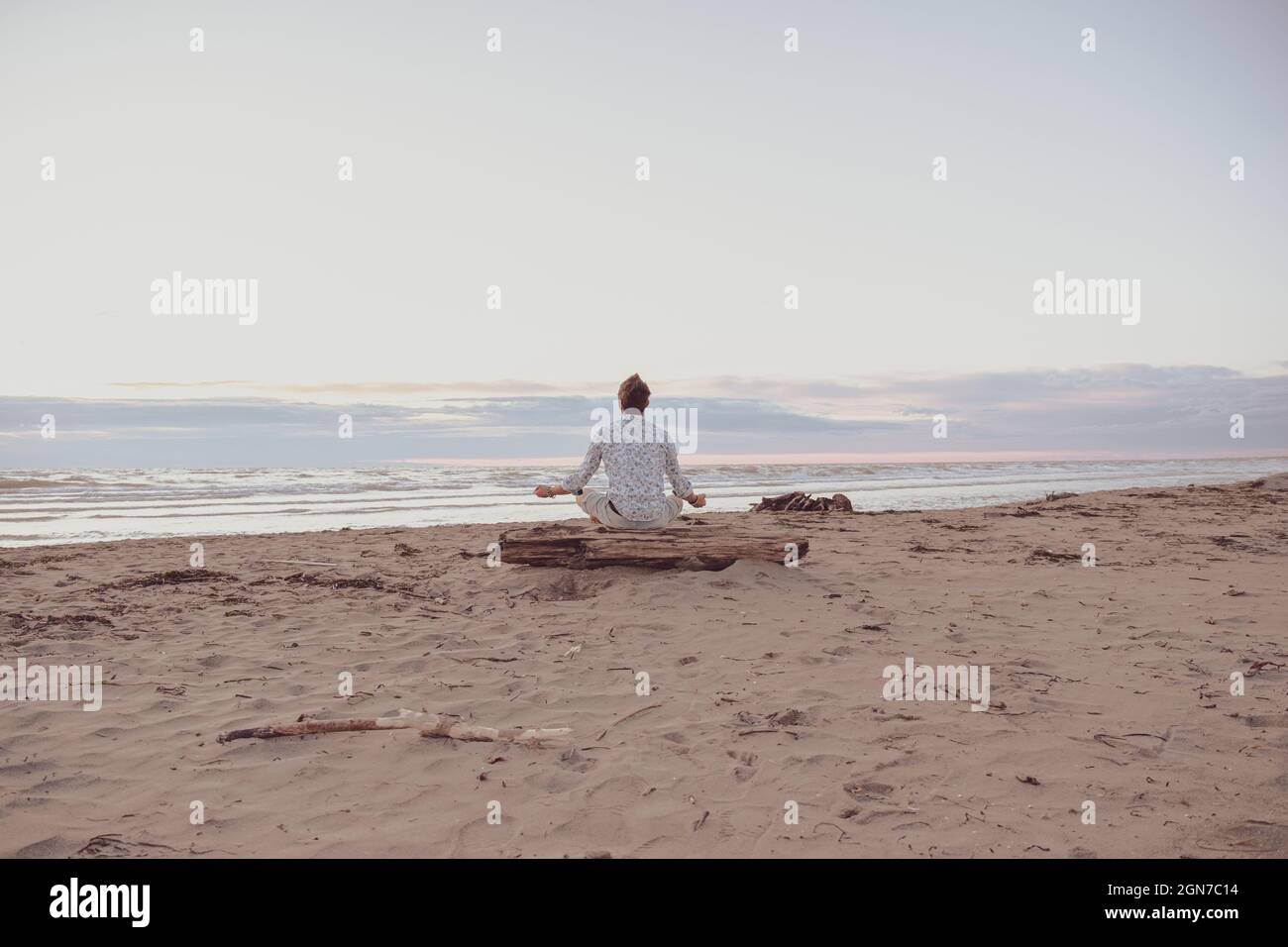 Ragazzo caucasico che pratica yoga al mare all'alba - uomo che pratica yoga posa alla meditazione sulla spiaggia al tramonto - sano con concetto di yoga Foto Stock