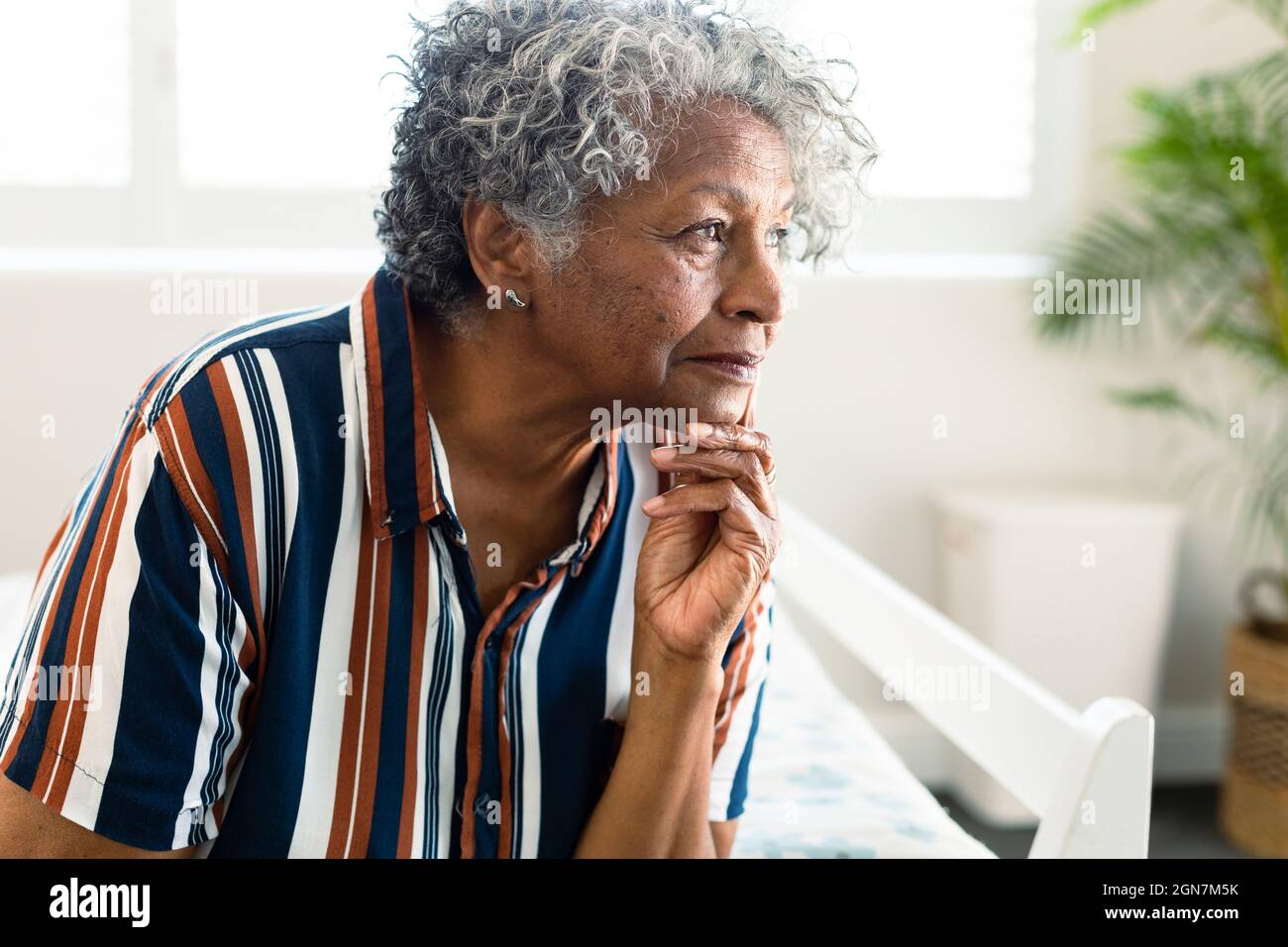 Ritratto della donna anziana afroamericana pensierosa seduta sul letto e guardare a distanza Foto Stock