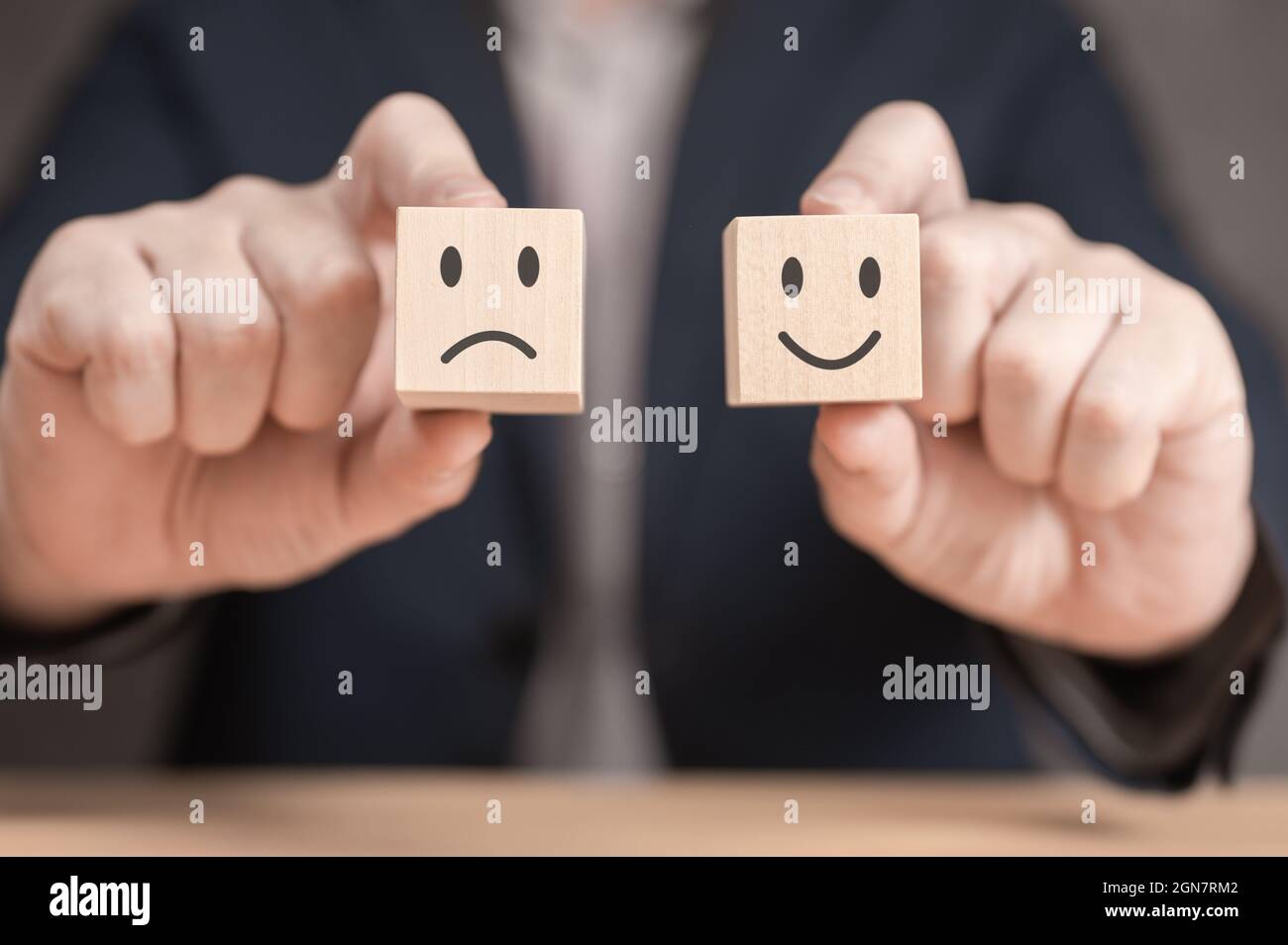 valutazione e revisione dei concetti. Concetto di classifica e soddisfazione del cliente. L'uomo d'affari ha due cubetti di legno con sorridente soddisfatto e diss Foto Stock