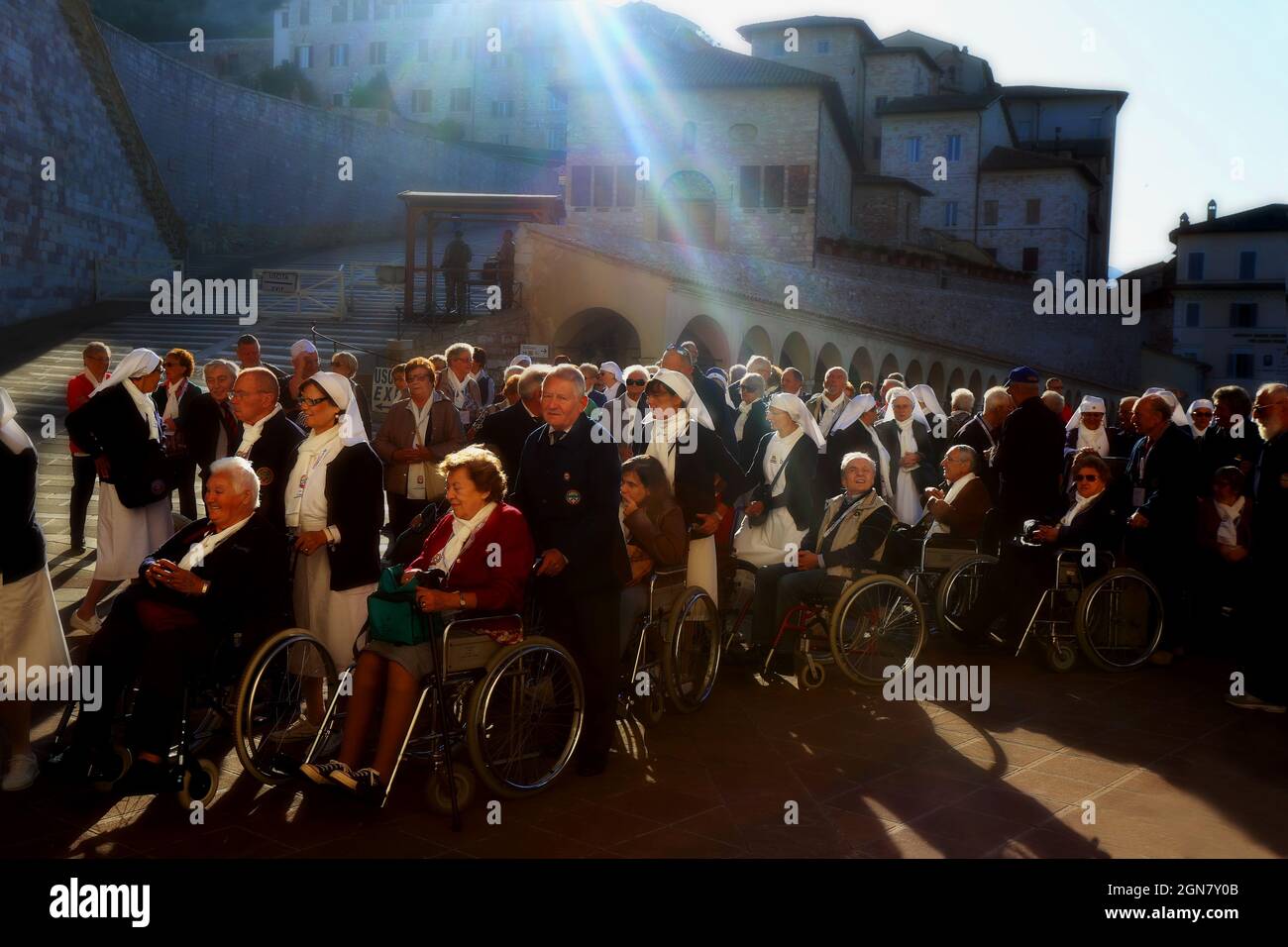 Menschen mit Behinderung oder Rollstuhlfahrer mit Nonnen vor der Kirche im mittelalterlichen Assisi in Umbrien Italien Foto Stock