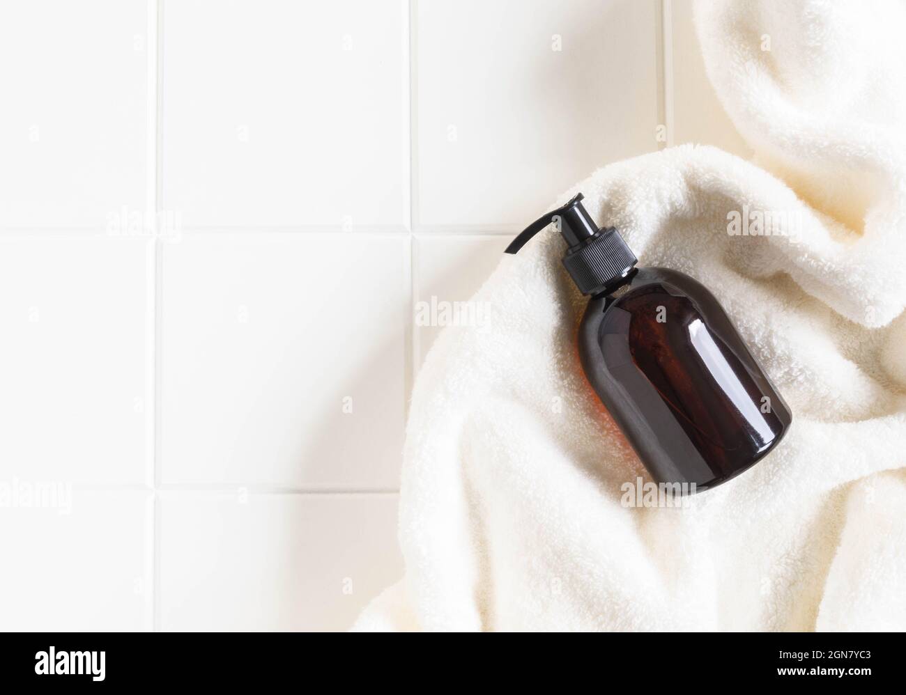 Mockup bottiglia marrone per prodotti da bagno in bagno, shampoo spa, gel doccia, sapone liquido su asciugamano di cotone piatto. Vista dall'alto. Spazio di copia Foto Stock