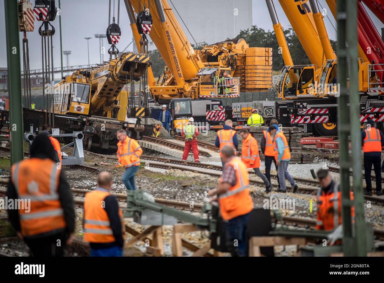 23 settembre 2021, bassa Sassonia, Emden: Le gru montate su autocarri vengono utilizzate per sollevare una gru per la costruzione di binari deragliati di peso superiore a 100 tonnellate. La gru per la costruzione di ferrovie è stata deragliata la scorsa settimana al molo di Borkum e ora deve essere recuperata. Foto: Sina Schuldt/dpa Foto Stock