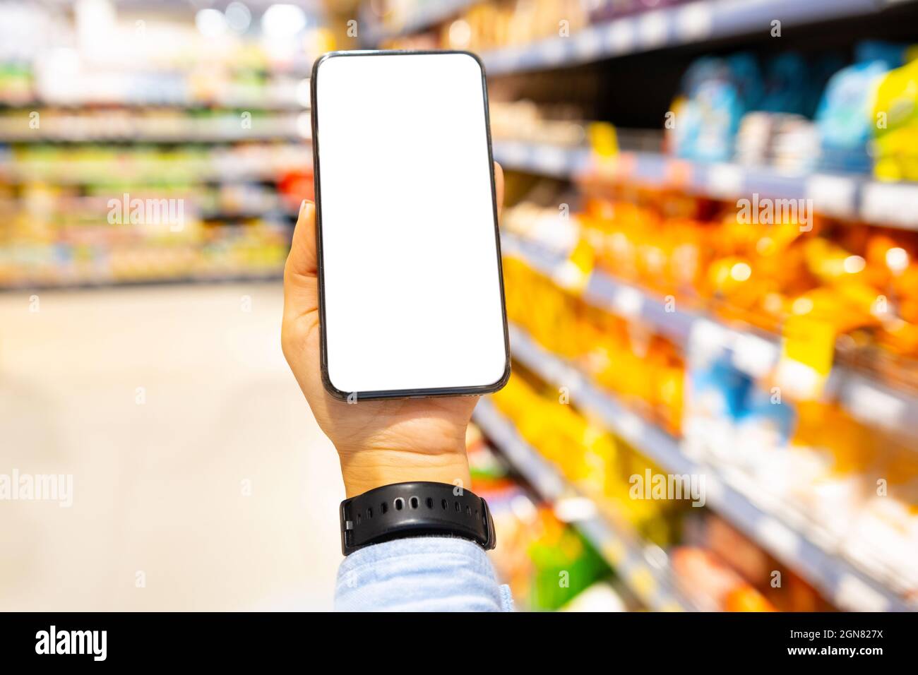 Foto ravvicinata di un orologio digitale indossato da un uomo che tiene lo  smartphone con lo schermo in negozio tra gli scaffali Foto stock - Alamy