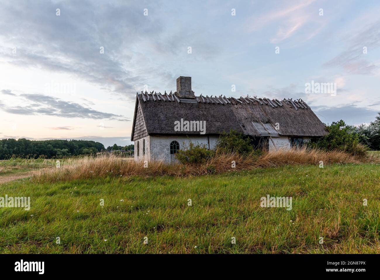 Una vecchia casa abbandonata con un tetto di paglia, solitario situato vicino al mare a Bisserup, Danimarca, 8 agosto 2021 Foto Stock