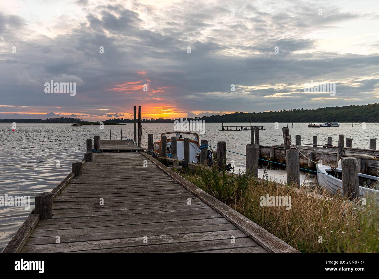 Un vecchio molo di legno con pali e barche al tramonto, Bisserup, Danimarca, 8 agosto 2021 Foto Stock