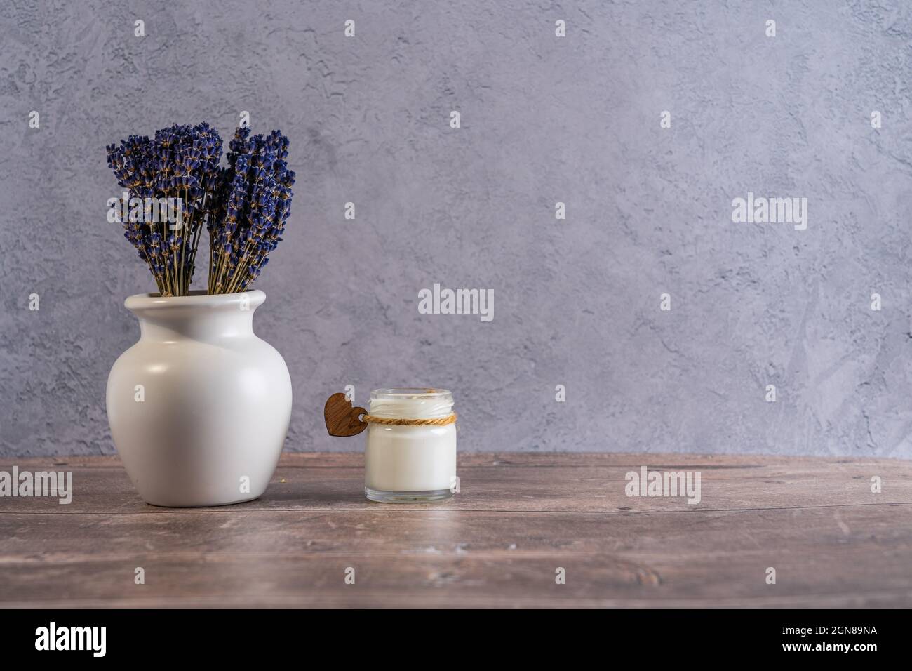 Candela fatta a mano in un whitejar con cuore di legno e un piccolo vaso con Lavanda mazzo Lifestyle Foto Stock