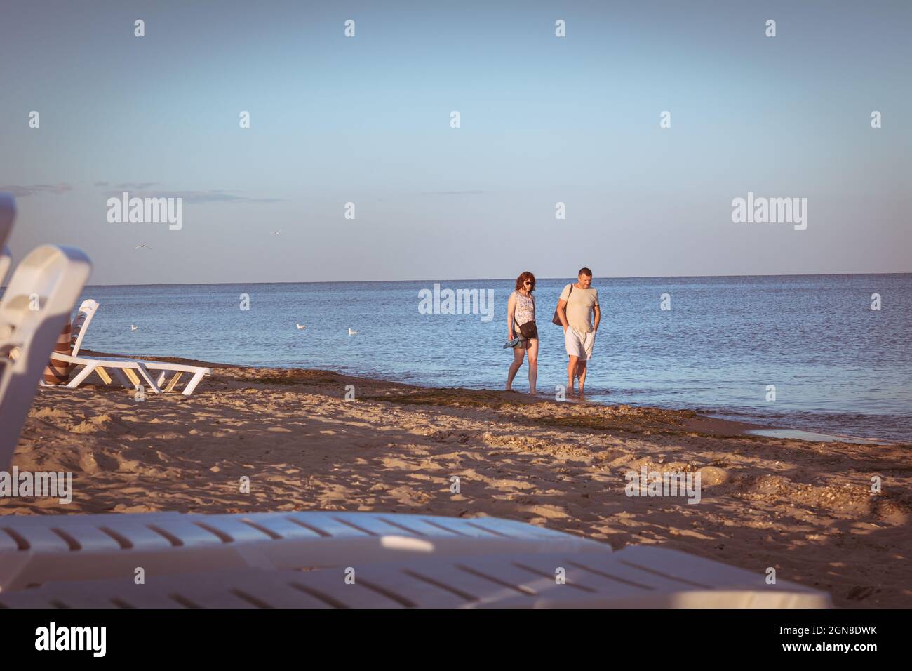Zatoka, Odessa, Ucraina - uomo e donna non identificati camminano lungo la sabbia lungo la costa del Mar Nero al tramonto Foto Stock