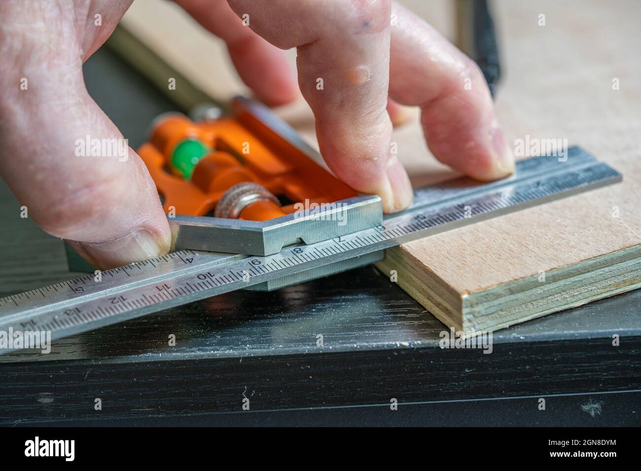 fuoco selezionato di misurazione di un angolo retto perfetto su un pezzo di compensato usando un quadrato calibrato regolabile Foto Stock