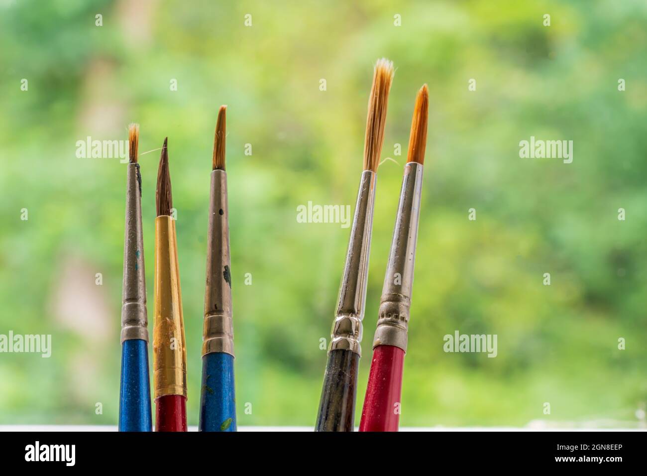 primo piano di cinque antichi artisti indossabili capelli biondi acquerello pennelli di vernice Foto Stock