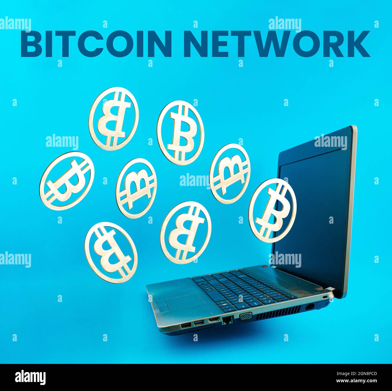 Parole di rete Bitcoin con monete d'oro che volano fuori dal portatile su sfondo blu. Concetto di rete aziendale di estrazione Bitcoin e criptovaluta virtuale Foto Stock