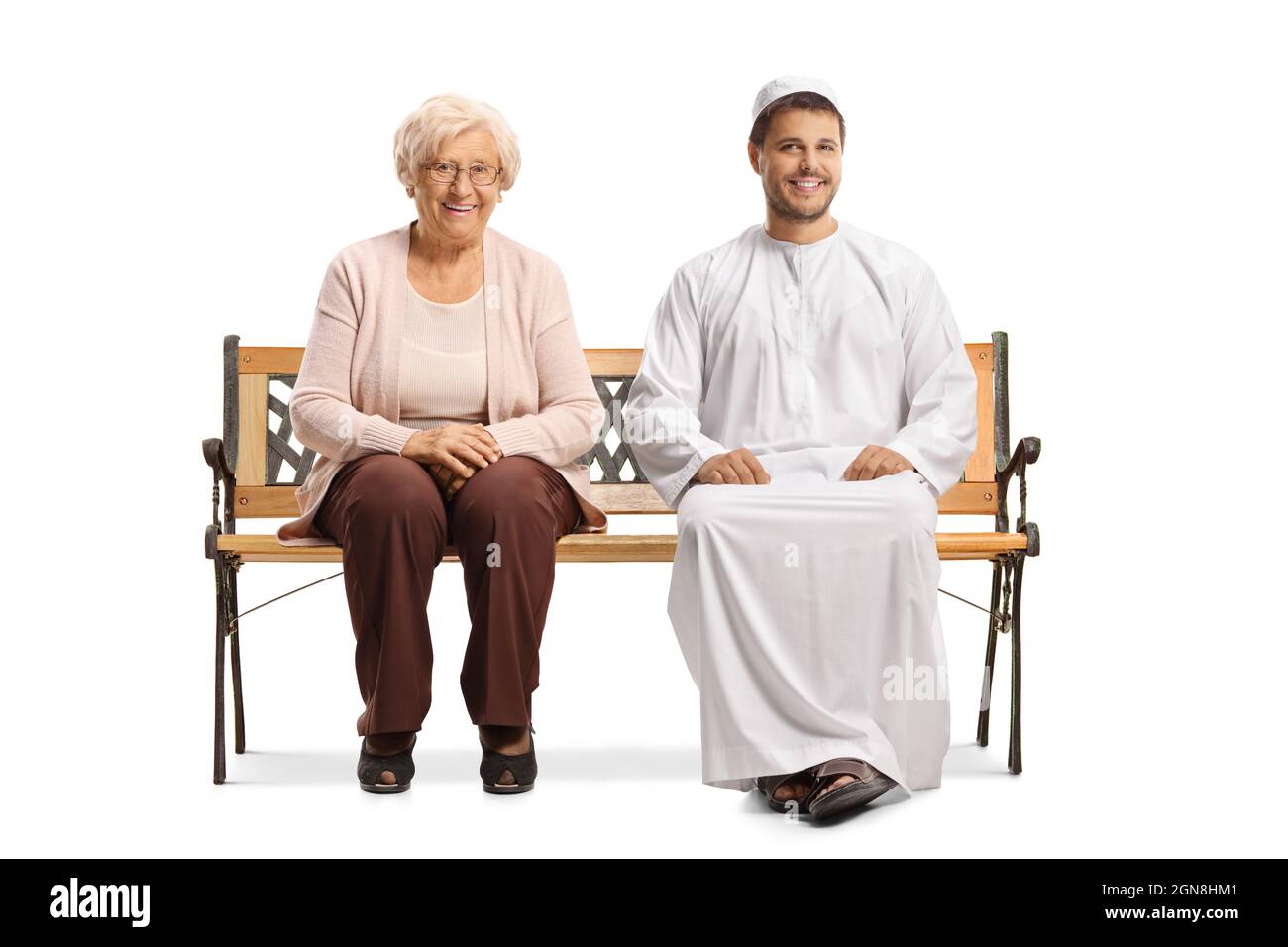 Giovane uomo in abiti etnici e una donna anziana seduta su una panca e sorridente isolato su sfondo bianco Foto Stock