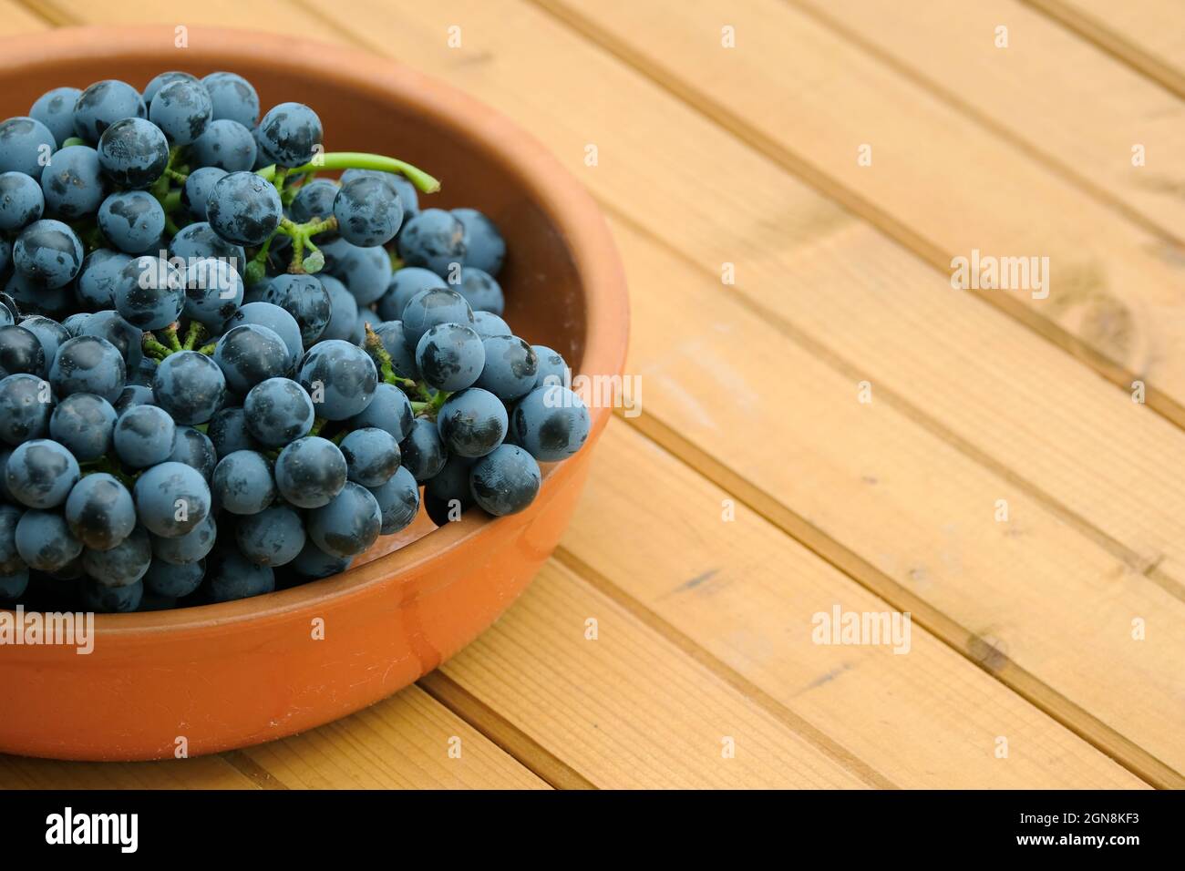 Lotto di acini rossi maturi sul mazzo in una ciotola rotonda marrone sul tavolo di legno vista frontale primo piano Foto Stock
