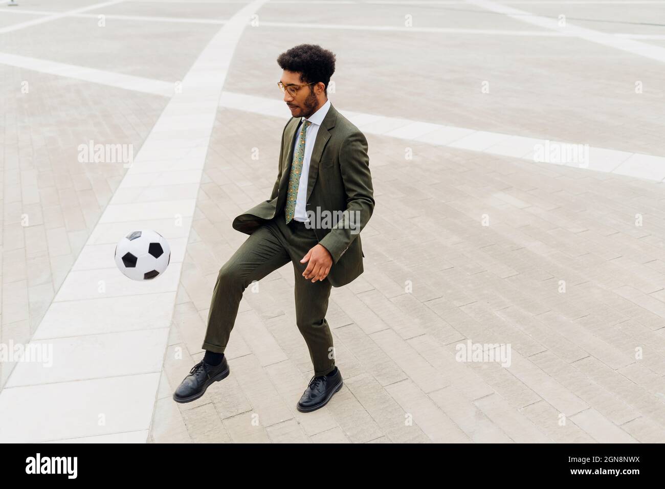 Uomo d'affari che gioca con la palla di calcio sul sentiero Foto Stock