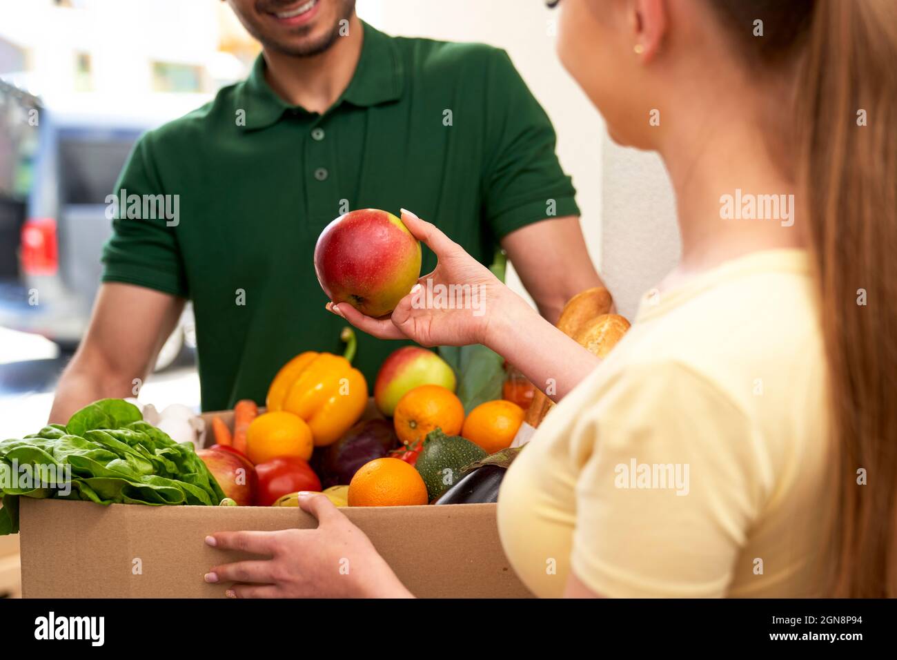 Donna che controlla la frutta mentre riceve l'ordine a casa Foto Stock