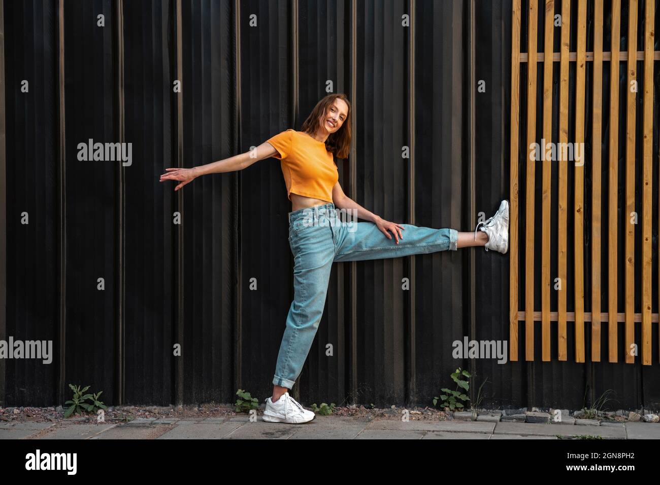 Donna sorridente appoggiata sul muro di colore nero Foto Stock