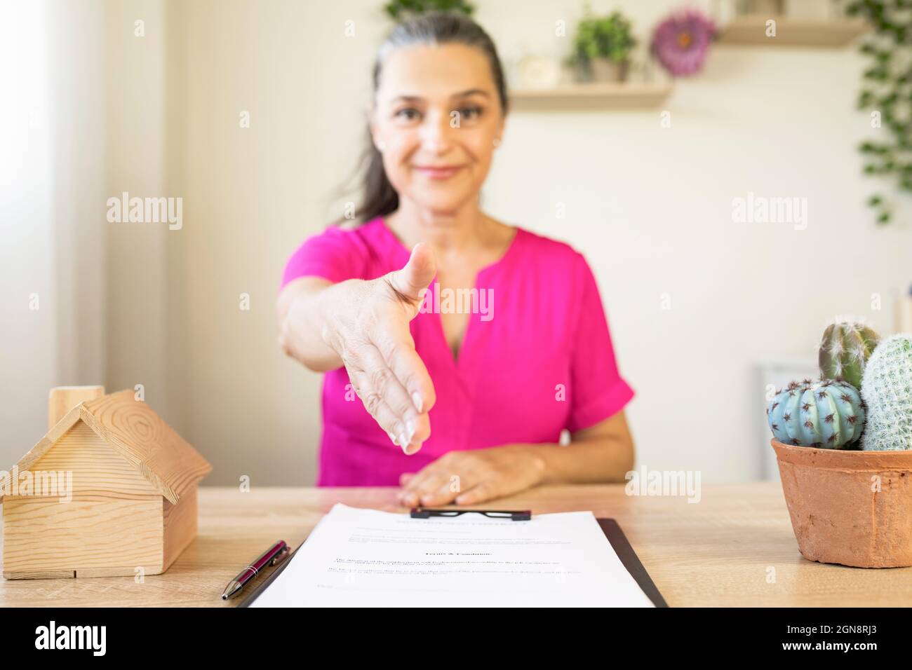 Agente immobiliare femminile che offre handshake in ufficio a casa Foto Stock