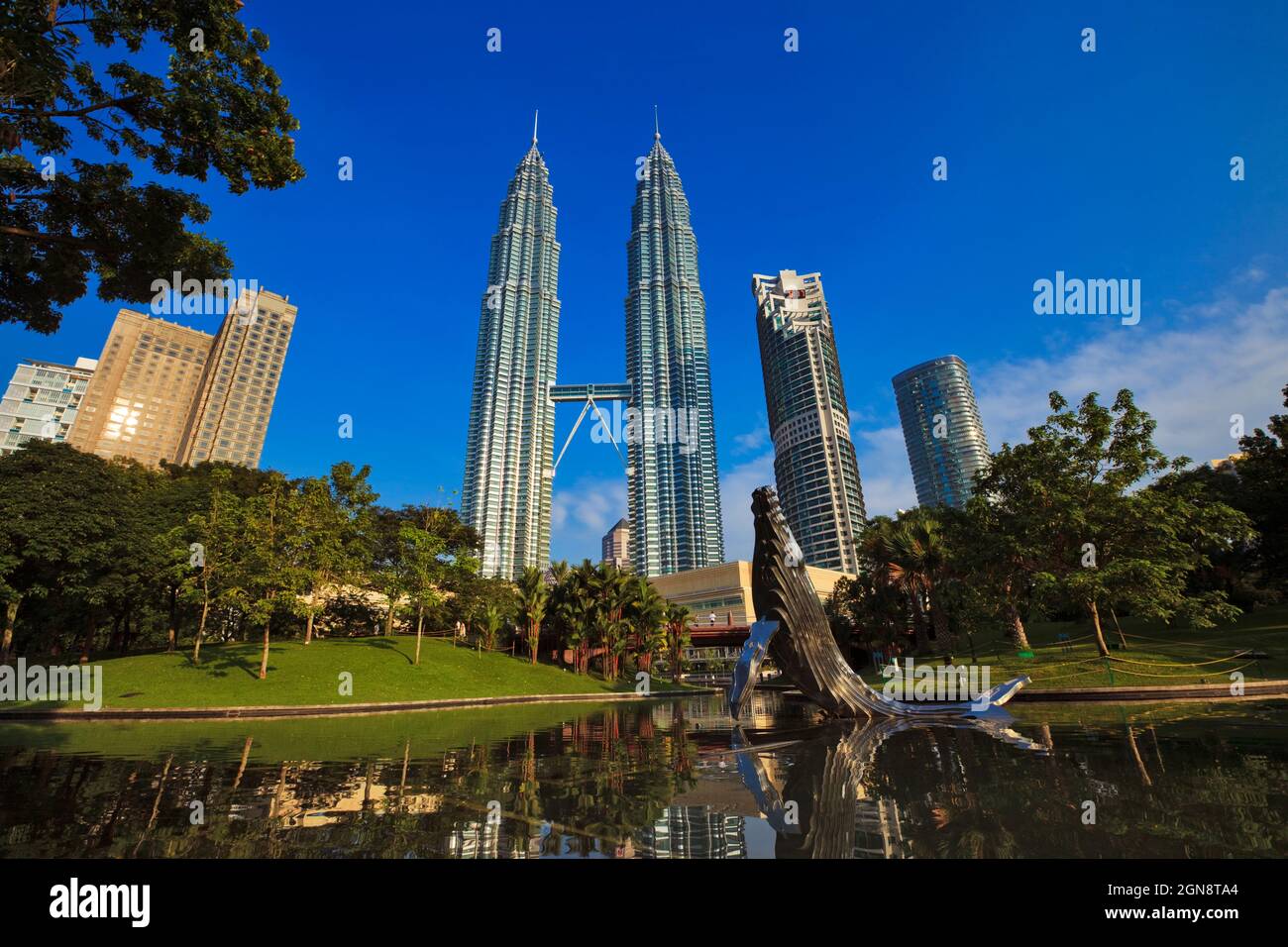 Malesia, Kuala Lumpur, Stagno e scultura balena nel Parco KLCC con Petronas Towers sullo sfondo Foto Stock