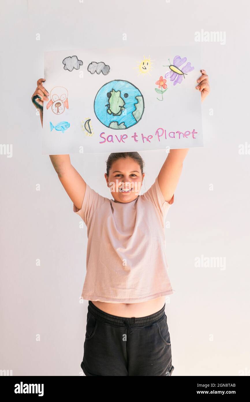 Ragazza sorridente che tiene il poster del pianeta Terra a casa Foto Stock