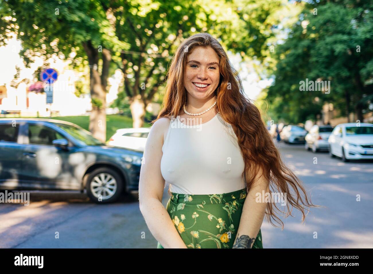 Donna sorridente con lunghi capelli in piedi sulla strada Foto Stock