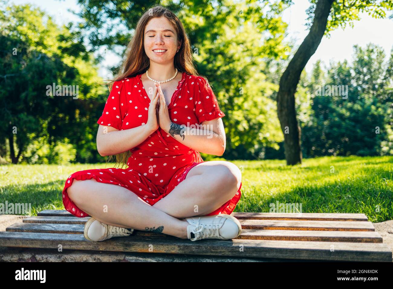 Donna rossa con le mani afflitto meditating al parco Foto Stock