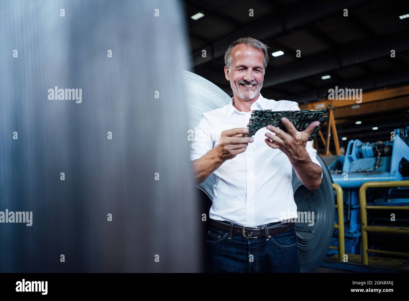 Uomo d'affari sorridente che controlla le attrezzature nell'industria del metallo Foto Stock