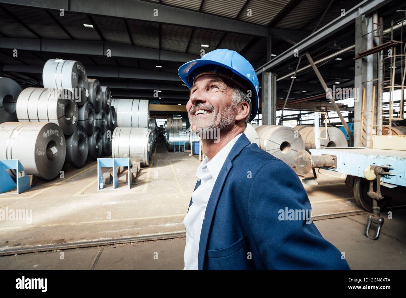 Sorridente maschio professionista con hardhat cercando in su Foto Stock