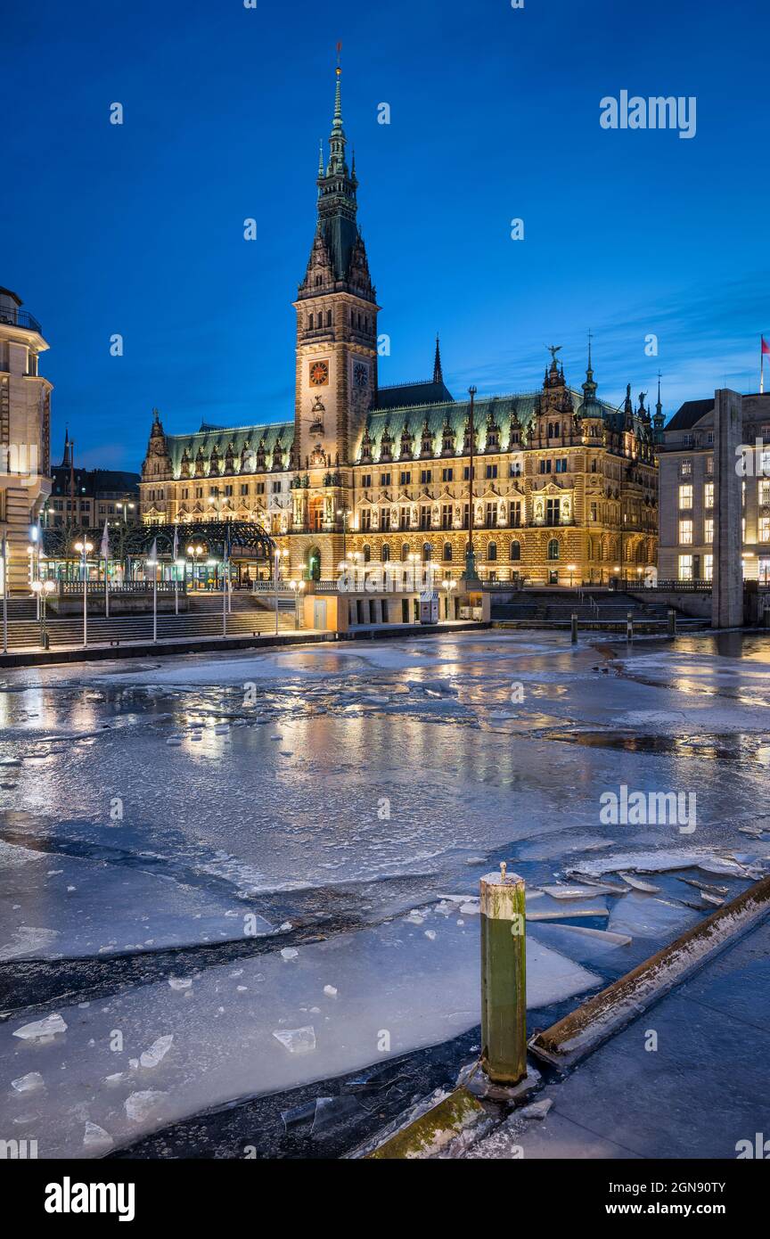 Germania, Amburgo, ghiaccio galleggiante nel canale della città al crepuscolo con il municipio di Amburgo in background Foto Stock
