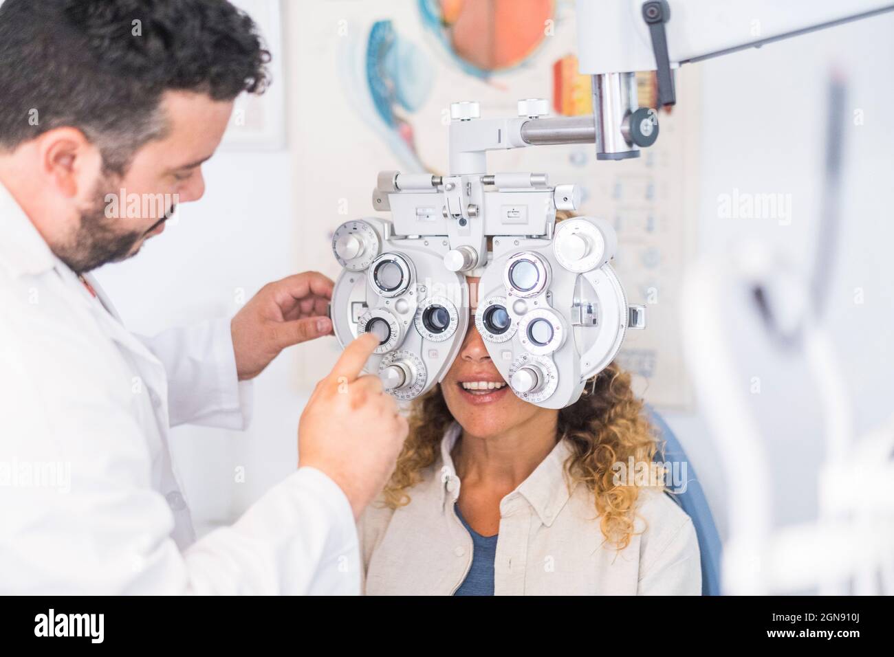 Forottero di regolazione optometristo maschile durante il controllo della vista della paziente femminile Foto Stock