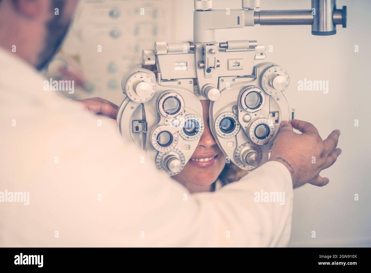 Oftalmologo maschile che esamina la vista del paziente attraverso il foropter in clinica Foto Stock