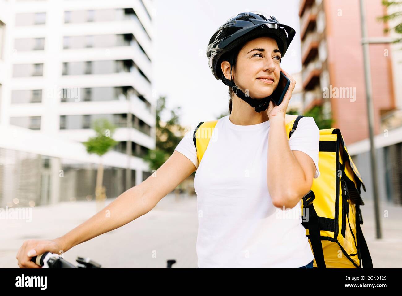 Donna di consegna che parla sul telefono cellulare in città Foto Stock