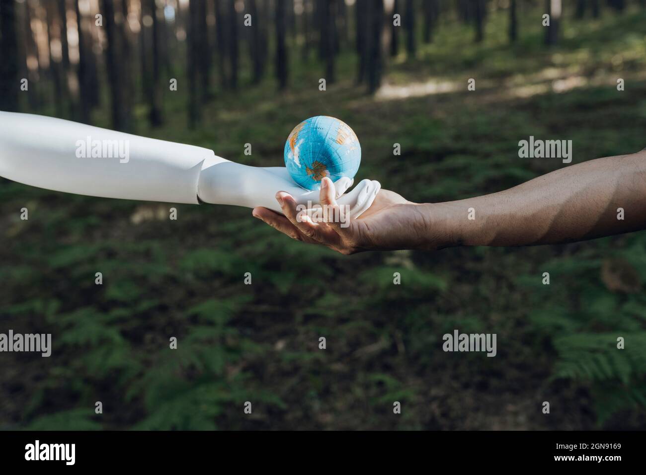 Uomo e robot che tengono insieme il globo terrestre nella foresta Foto Stock