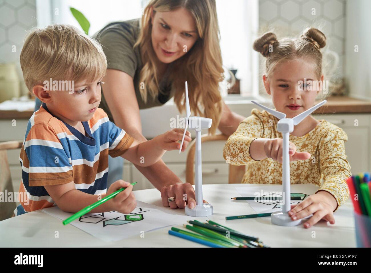 Madre che insegna circa il modello di turbina eolica ai bambini nel paese Foto Stock