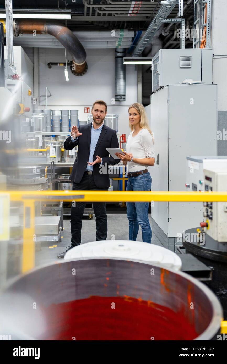 Professionista maschile che condivide esperienza con collega femminile in fabbrica di verniciatura Foto Stock