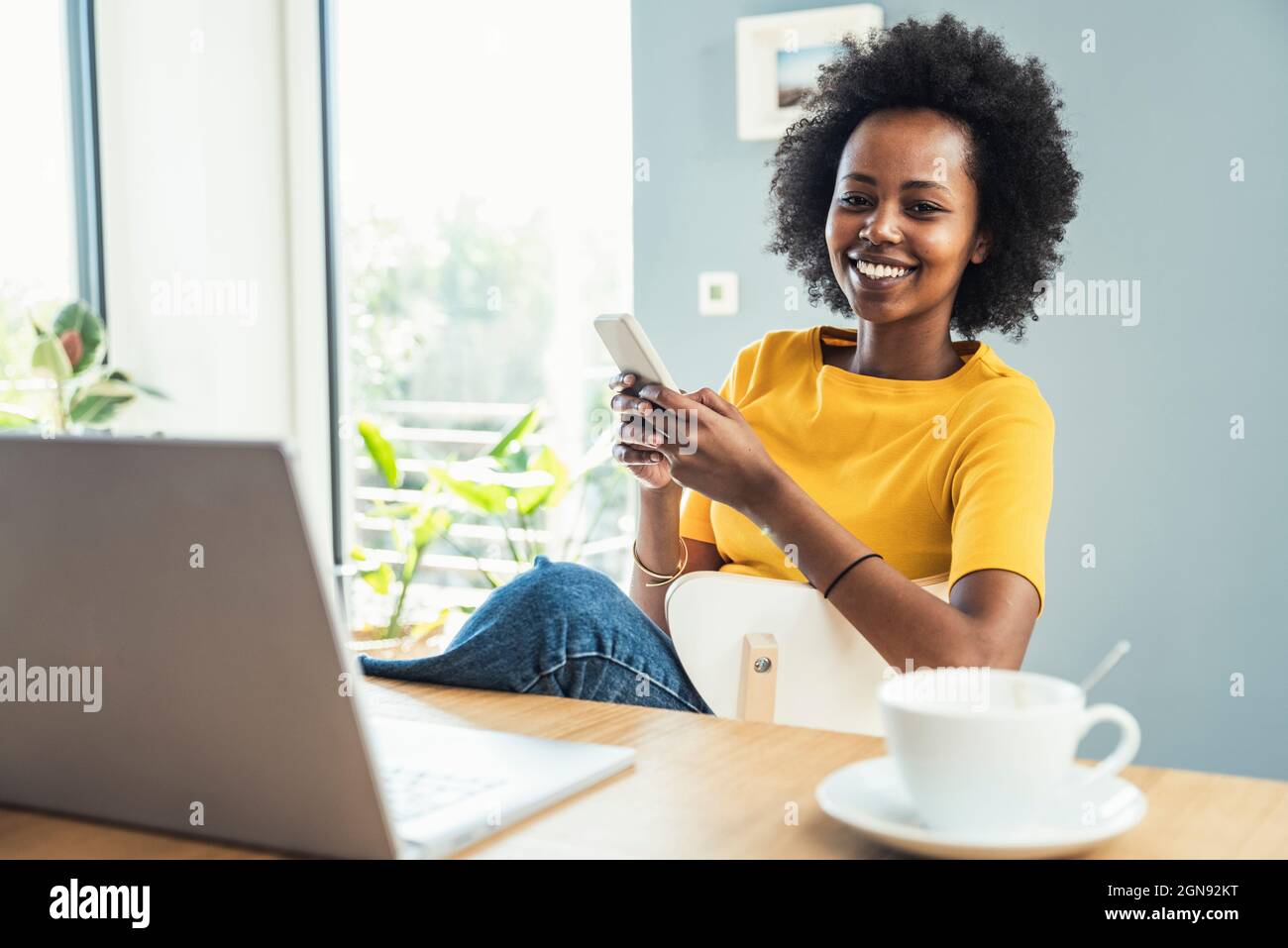 Freelance femminile con smartphone in ufficio Foto Stock