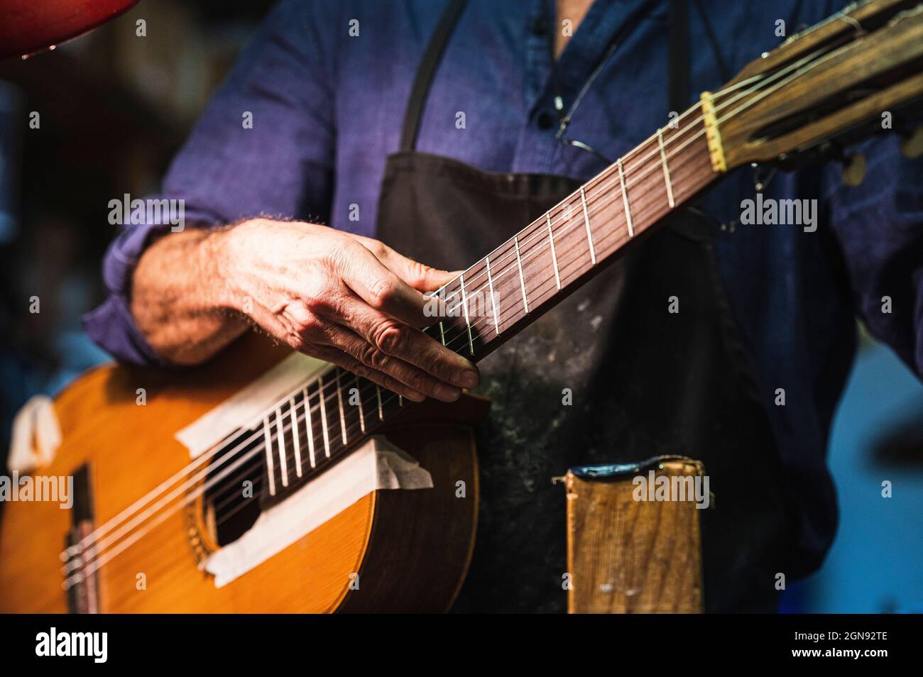 Luthier controllare le corde di chitarra in officina Foto Stock