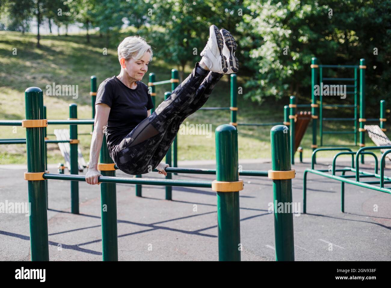 Donna in equilibrio con i piedi in su sulle attrezzature di esercitazione al parco Foto Stock