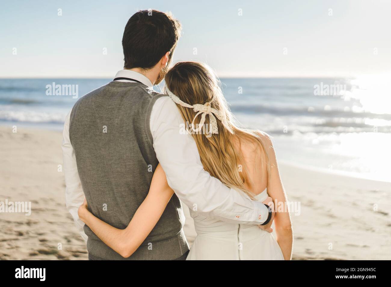 Coppia appena sposata con braccio intorno in piedi sulla spiaggia Foto Stock