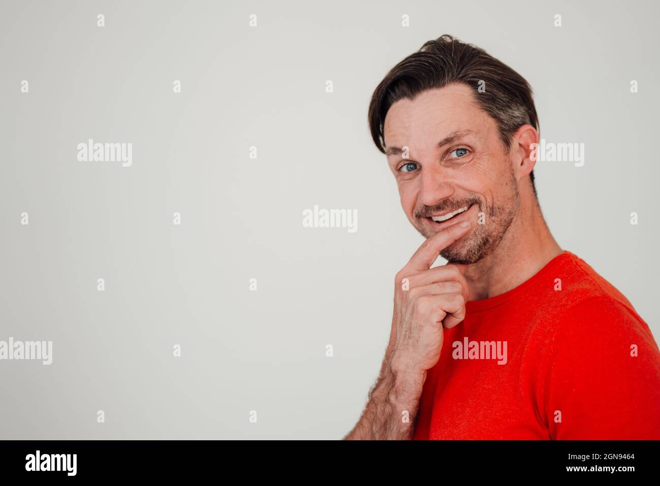 Uomo maturo sorridente con peli corti davanti alla parete bianca Foto Stock