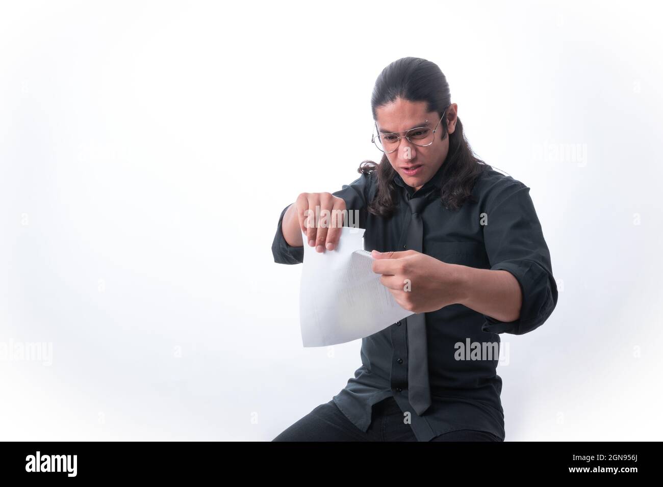 Persona su sfondo bianco. Sta strappando una pagina perché si è arrabbiato di qualcosa che ha letto. Vestito in abiti formali. Spazio bianco. Uomo gesticul Foto Stock