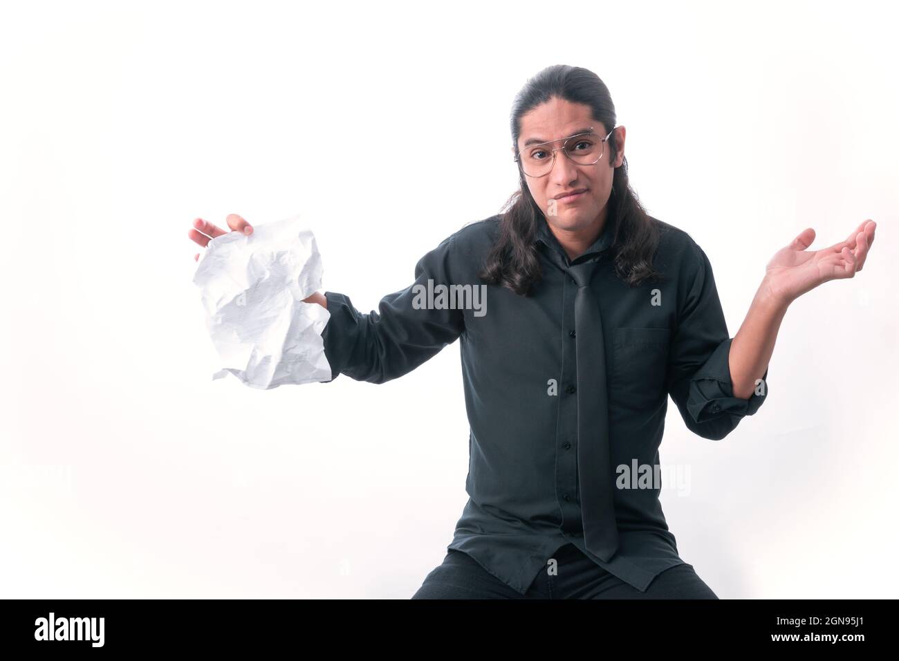 Uomo su sfondo bianco. Verso la macchina fotografica che mostra di non conoscere la risposta e ha un foglio strappato in mano. Vestito con abiti formali. Spazio bianco Foto Stock