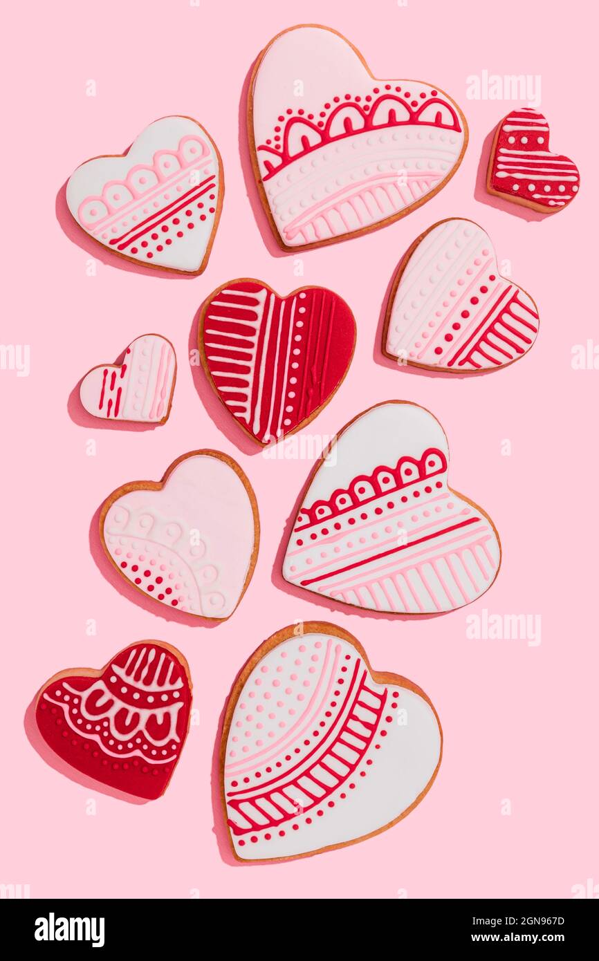 Modello di biscotti a forma di cuore rosso con uno singolo che si stita fuori Foto Stock