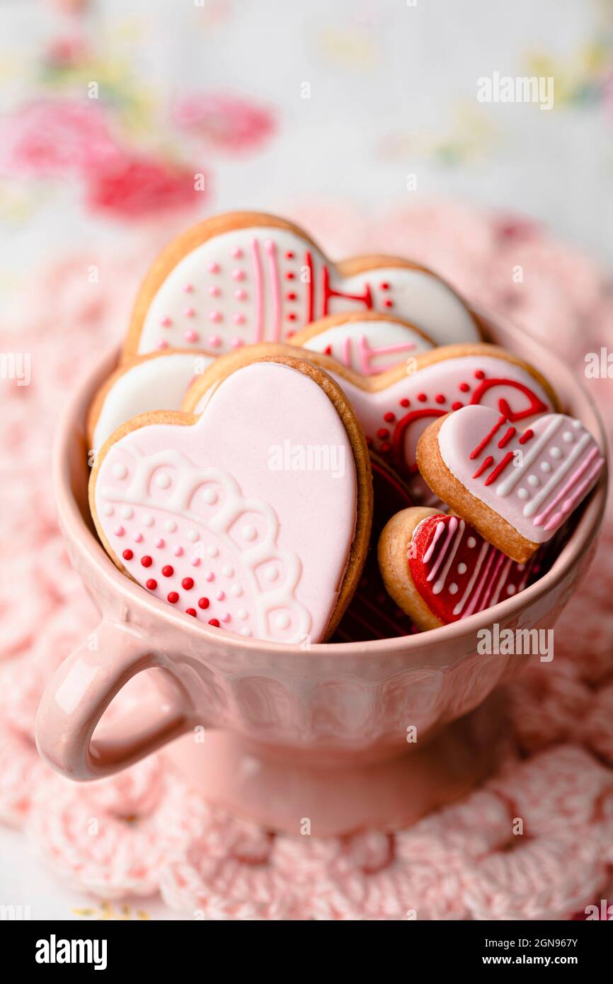 Shot studio di ciotola di miele, cucchiaia di miele e mini torte appena sfornate a forma di cuore Foto Stock