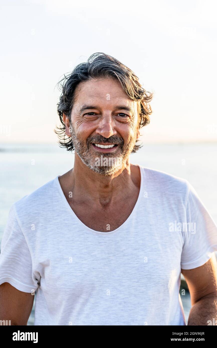 Uomo maturo felice in piedi in spiaggia Foto Stock