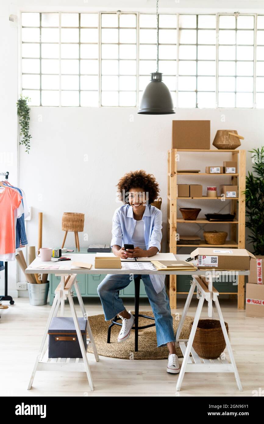 Stilista di moda femminile che parla su smartphone mentre lavora in studio Foto Stock