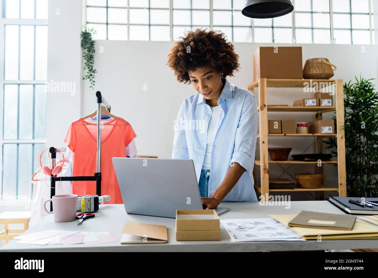 Stilista di moda femminile che utilizza un computer portatile mentre lavora in studio Foto Stock
