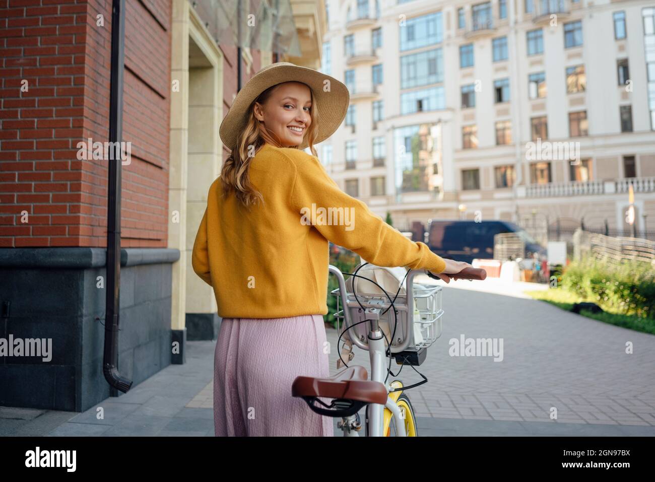 Giovane donna che guarda sopra la spalla mentre ruota la bicicletta sul sentiero Foto Stock