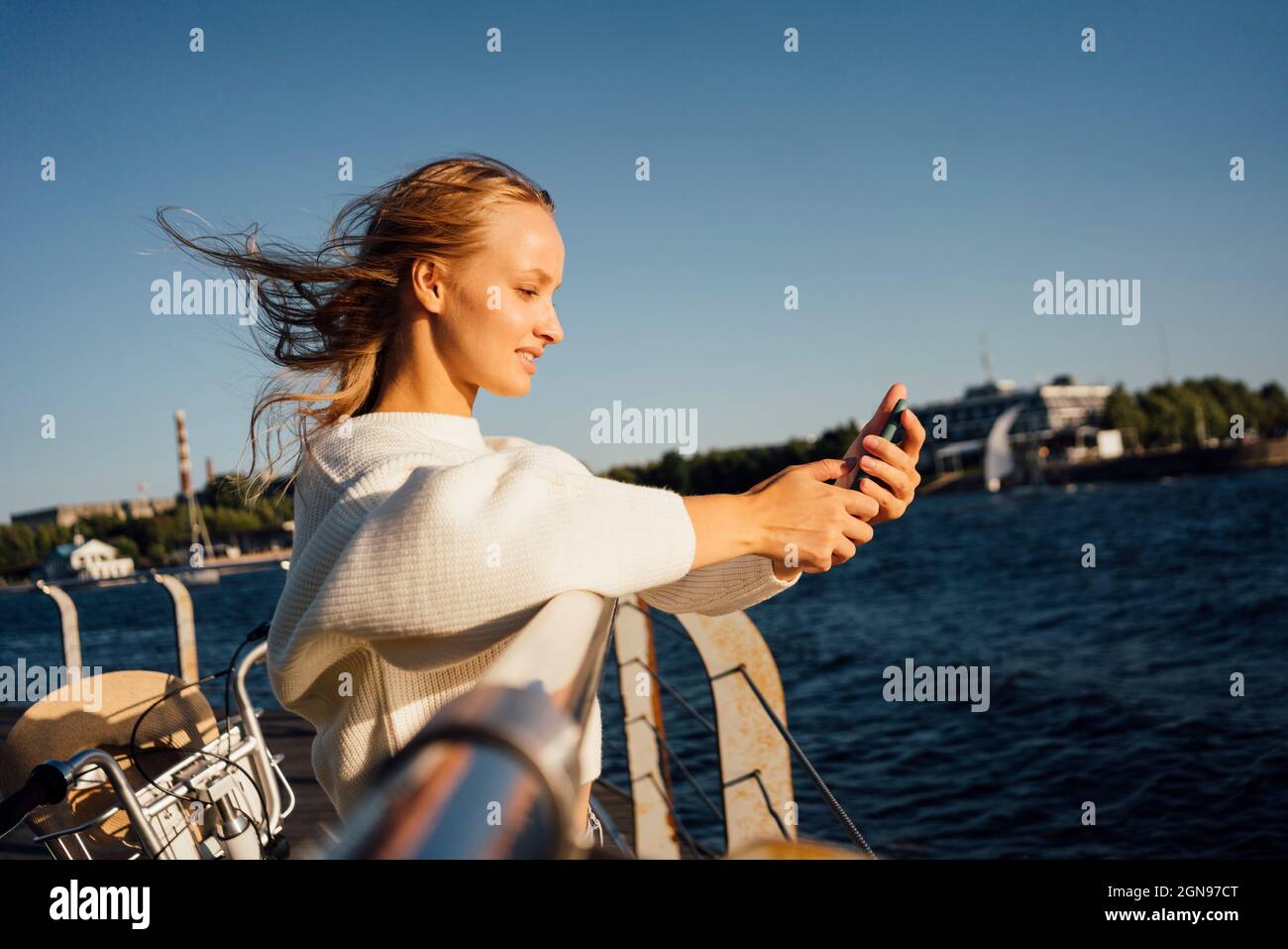 Donna che usa lo smartphone mentre si trova in piedi accanto alla ringhiera Foto Stock