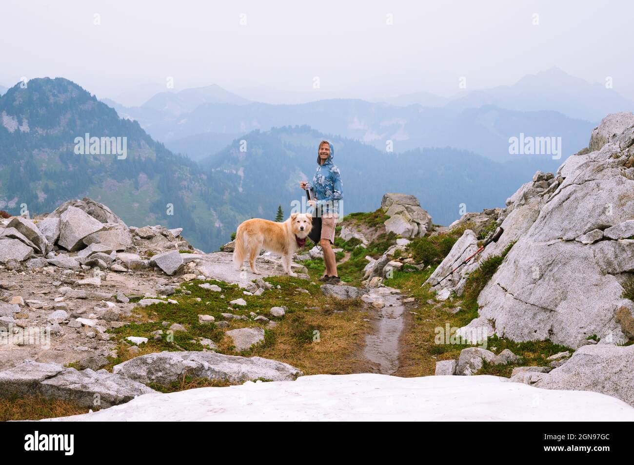 Escursionista e cane sorridente nella cascata nord montagne alpine Foto Stock